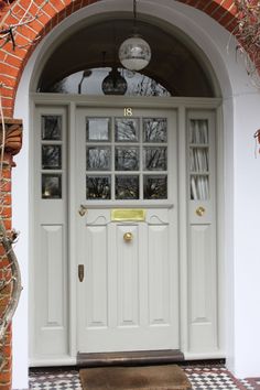 a white front door with glass panes on the top and bottom, flanked by a checkerboard tile floor