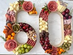 the number 50 made out of fruits and vegetables is decorated with meats, cheeses, and fruit