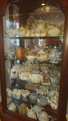 a display case filled with lots of different types of teapots and saucers