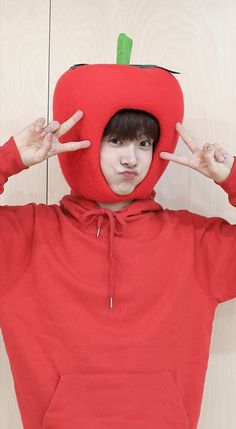 a young boy wearing a red hoodie with an apple on it's head