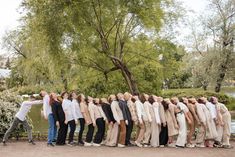 a group of people standing next to each other in front of a tree and water