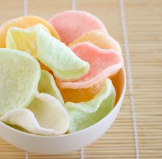 a white bowl filled with fruit slices on top of a bamboo mat next to a wooden table