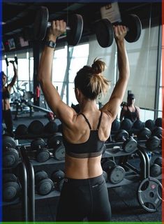 a woman lifting two dumbbells in a gym