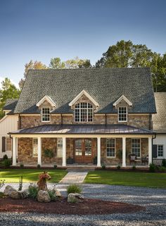 a large brick house with white columns and windows on the front, surrounded by graveled driveway