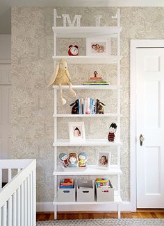 a white book shelf filled with books next to a baby's crib in a room