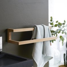 a towel hanging on the side of a wall next to a black sink and potted plant