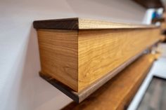 a close up of a wooden shelf with a white wall in the background and wood trim around it