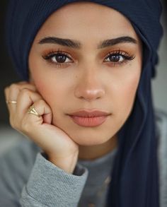 a woman wearing a hijab with her hand on her chin and looking at the camera