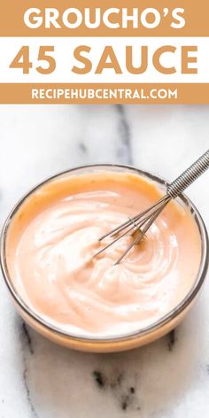 a bowl filled with sauce sitting on top of a marble counter next to a whisk