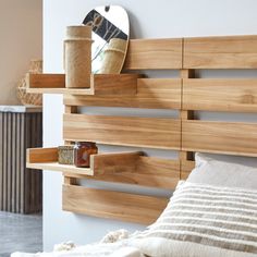 a bed with wooden headboard and shelves on the wall, next to a mirror