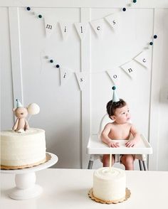 a baby sitting in a high chair next to a cake