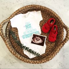 a basket with shoes, t - shirt and baby booties on it that says guess what?