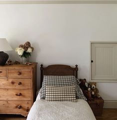 a bedroom with a bed, dresser and lamp on the side table in front of it