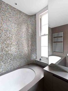 a bathroom with a bathtub, sink and large mirror in it's corner