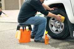 a man is cleaning the tire of a white truck with yellow sponges on it