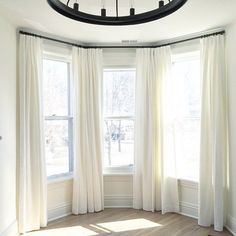 an empty room with white curtains and a round window