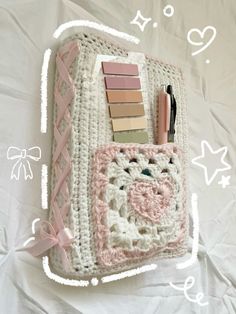 a crocheted purse with some pens and pencils in it on a white sheet