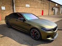 a gold car parked in front of a brick building