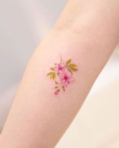 a small pink flower tattoo on the arm