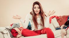 a woman sitting on top of a couch with her hands in the air and looking surprised