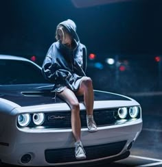 a woman sitting on the hood of a car