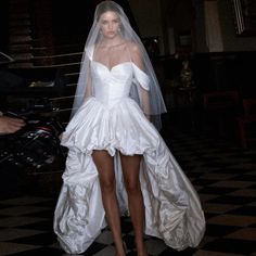 a woman in a white wedding dress with a veil on her head and heels on the ground