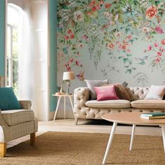 a living room filled with furniture next to a large flowered wallpaper covered in flowers