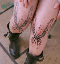 a woman's legs with tattoos and boots on her feet, both showing butterflies