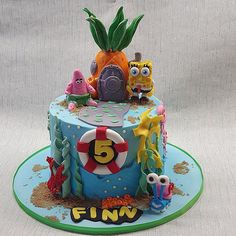 a birthday cake decorated with spongebob characters and pineapple on the top tier