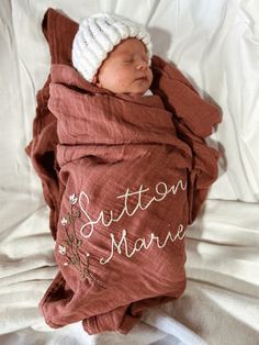 a newborn baby wrapped in a blanket with the words susten marine written on it