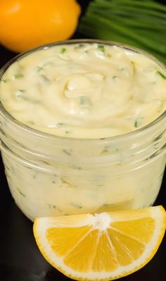 a glass jar filled with lemon custard dip next to an orange slice on a black surface