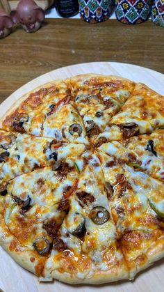 a pizza sitting on top of a wooden plate covered in cheese and toppings,