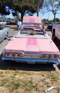 an old pink car parked in a parking lot