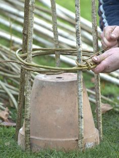 a person is working on an old bell in the grass with sticks and branches behind it