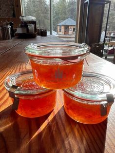 three jars filled with liquid sitting on top of a wooden table