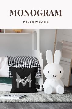 the monogram pillow case is shown next to a stuffed bunny and other items on a rug