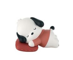 a small white and black dog laying on top of a red object with its eyes closed