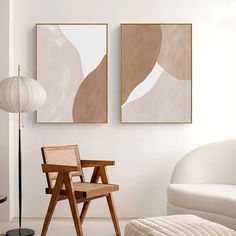 two abstract paintings hang on the wall above a chair and ottoman in a living room