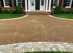 a driveway with gravel and grass in front of a house