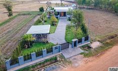 an aerial view of a house in the middle of a dirt field with lots of trees