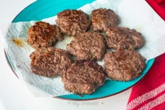 a blue plate topped with meat patties on top of a red and white cloth