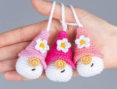 three crocheted toys are being held in someone's hand while wearing pink and white hats