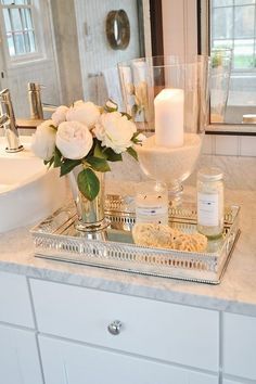 a bathroom vanity with flowers and candles on it