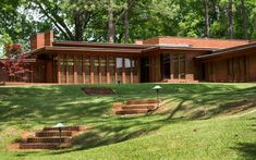 a large house sitting on top of a lush green field next to a tree filled forest