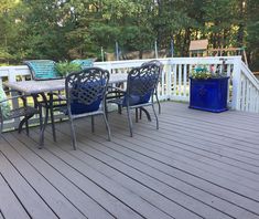 a table and chairs on a deck with trees in the backgroung area