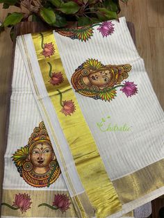 two white and yellow sari with an image of buddhas on the side, sitting next to a potted plant