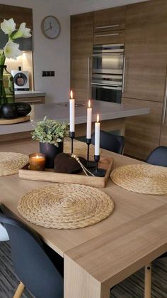 a wooden table with candles on it in a modern style kitchen and dining room area