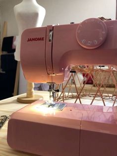 a pink sewing machine sitting on top of a table next to a white mannequin