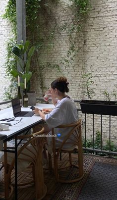 a woman sitting at a table in front of a laptop computer