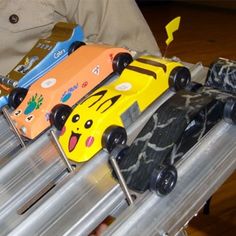 toy cars are lined up on top of a metal rack in front of a man